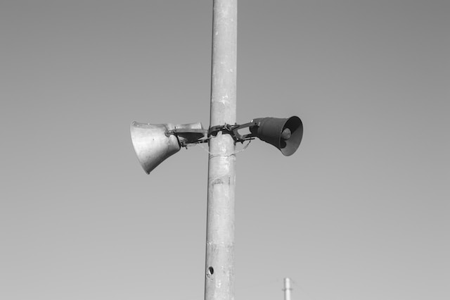 two speakers from an old PA system attached to a pole