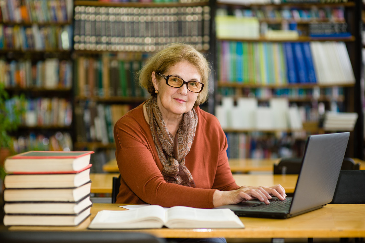 Senior woman using laptop in library